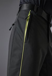 Pantalones negros con una textura suave que presentan un acento en cremallera de color amarillo neón y una cinturilla ajustable para un ajuste seguro.