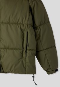 Kurtka puchowa w oliwkowym zielonym kolorze z przeszywanymi panelami, kieszeniami bocznymi oraz regulowanym sznurkiem u dołu. Materiał wydaje się gładki i wodoodporny.