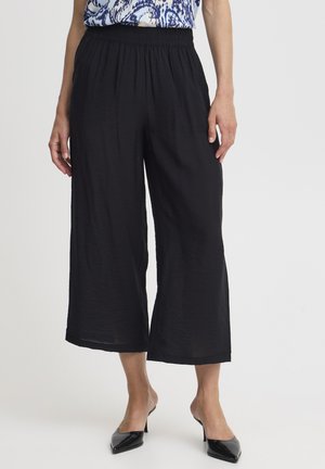 Pantalones anchos negros con cinturilla elástica, hechos de un tejido ligero y texturizado. Presentan un corte relajado y un dobladillo a la altura del tobillo.