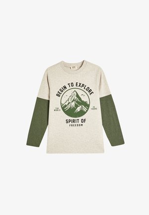 T-shirt a maniche lunghe grigio chiaro con maniche verde scuro. Presenta una grafica di montagne e il testo "Inizia a Esplorare Spirito di Libertà." Tessuto morbido.