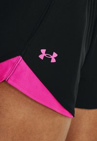 Černé sportovní šortky s růžovým akcentem na lemu. Na bočním švu je růžové logo Under Armour. Vyrobené z elastické tkaniny.