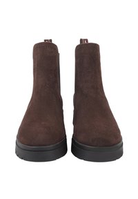 Bottes de cheville en suède marron avec une texture lisse, bout arrondi et semelle en caoutchouc noir. Présente des coutures minimales et des languettes pour faciliter l'enfilage.