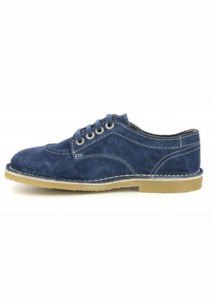 Zapato azul de ante con suela beige, presenta seis ojales, costuras blancas en contraste y puntera redondeada, mostrando un diseño clásico.