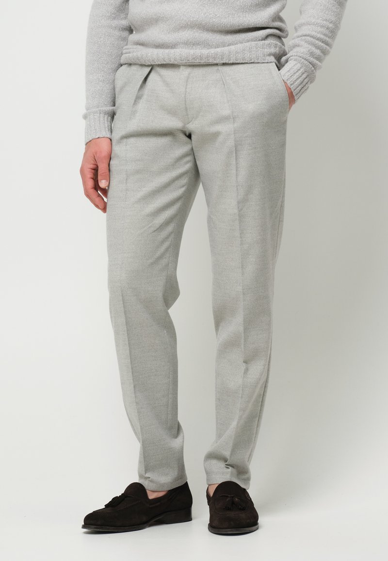 Lichtgrijze op maat gemaakte broek met een gladde textuur, geplooide voorkant, zijzakken en gecombineerd met donkerbruine suède instappers.