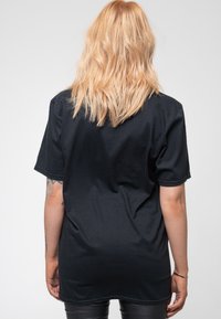 Black cotton T-shirt with short sleeves, crew neckline, and a loose fit. Smooth texture and simple design without embellishments.