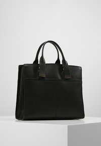 Svart läder tote väska med dubbla ovandelshandtag, vertikala sömmar och en framficka. Slät textur och strukturerad rektangulär form.