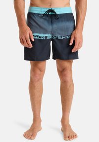 Shorts de bain en dégradé de bleu et noir avec une taille turquoise. Équipés d'un cordon de serrage et du logo Quiksilver le long de l'ourlet.