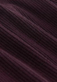 Țesătură ribbed violet, cu o textură moale, având linii verticale și variații ușoare în nuanțe, creând adâncime și dimensiune.