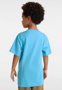 Světle modré bavlněné tričko s krátkými rukávy a kulatým výstřihem, s hladkým povrchem. Zadní pohled neukazuje žádné viditelné vzory ani kování.