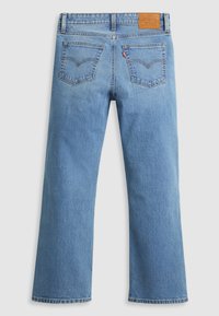 Jean en denim bleu clair avec une coupe droite, cinq poches et une étiquette en cuir sur la ceinture avec les détails de la marque.