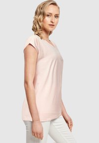 Lys rosa bomull V-hals T-skjorte med korte, rullede ermer, med en subtil trykt detalj på brystet og en avslappet passform.