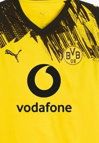 Camiseta de fútbol amarilla y negra del Borussia Dortmund con el logo de Puma y el patrocinador Vodafone en el frente, con el escudo del club que tiene dos estrellas.