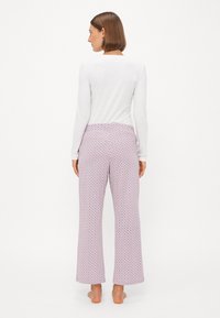Långa, mönstrade pyjamabyxor i ljusrosa och blå cirkulära mönster, tillverkade av ett mjukt, lätt material och med elastiskt midjeband.