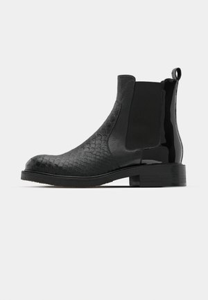 Cizme Chelsea negre cu un design texturat din piele de șarpe pe vârf și piele lucioasă și netedă la toc, având dungi elastice pe laterale.