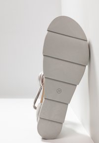 Semelle de chaussure gris clair avec un design segmenté, présentant une texture lisse et un indicateur de taille en relief "38" près du talon.
