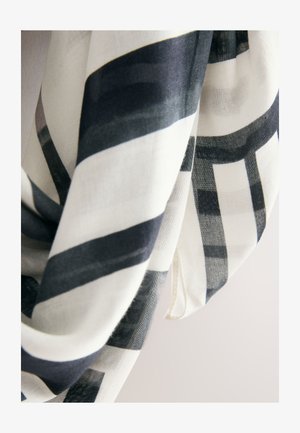 Lengvas šalikas su juodai balta dryžuota rašto su skirtingo pločio juostelėmis, baigtas subtiliu krašteliu. Minkštas, šiek tiek permatomas audinys.