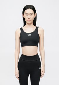 Fekete, rugalmas anyagból készült crop top kerek nyakkivágással és logó részlettel. Hozzáillő magas derekú leggingsszel párosítva.