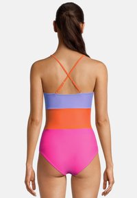 Kleurvolle badpak met kruisbanden. Voorzien van verticale kleurvlakken in lila, oranje en felroze. Soepele, rekbare stof.