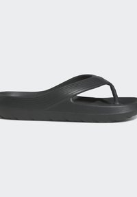 Svart gummisklippar, med ett texturerat övre band med en mellanrumsdesign och en robust sula med ett ruggat mönster för grepp.