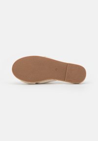 Plat schoenzool met een gestructureerd bruin rubberen oppervlak en een beige onderzijde; heeft een eenvoudig, glad ontwerp zonder zichtbare accenten.