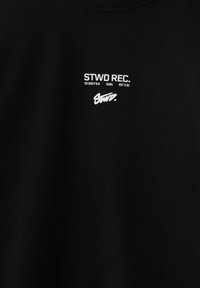 Tissu noir avec texte blanc "STWD REC. 00000P68 0091 EST 091" au-dessus d'un logo stylisé "Stwd." au centre.