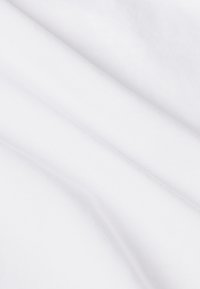 Tejido de algodón blanco con una textura suave y mate, que presenta pliegues suaves y sutiles patrones de tejido, demostrando cualidades ligeras y transpirables.