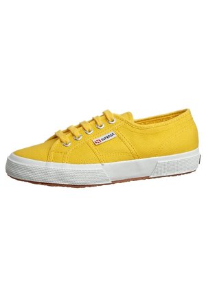 Lavtop gul lærredsneaker med hvid gummisål og snørebånd, metaløjehuller og et lille Superga-mærke på siden.