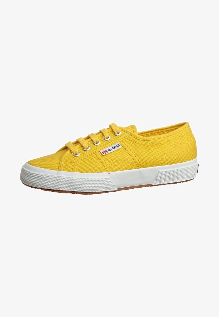 Baskets basses en toile jaune avec semelle en caoutchouc blanche et lacets, œillets métalliques, et une petite étiquette de marque Superga sur le côté.