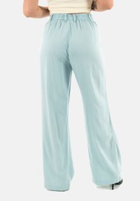 Pantaloni a gamba larga in tessuto blu chiaro con una cintura elastica, caratterizzati da una texture morbida e un design fluente.