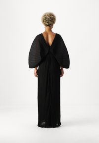 Juoda plisuota suknelė su giliu V formos atvartu ir didelėmis rankovėmis, pasižyminti sklandžiu dizainu ir švelniu tekstūru, suteikianti elegantišką siluetą.
