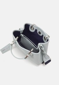 Jasnoniebieska skórzana torebka z srebrnymi okuciami, kieszenią wewnętrzną i ciemnoniebieską podszewką. Wyposażona w krótkie uchwyty i regulowany pasek.