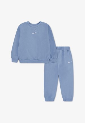 Modrý bavlněný set mikiny a kalhot s žebrovanými manžetami a pasem, s bílým logem Nike na hrudi a nohavici kalhot.