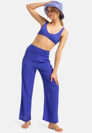 Blue ribbed crop top and wide-leg pants with an elastic waistband. A matching blue and white striped bucket hat completes the outfit.