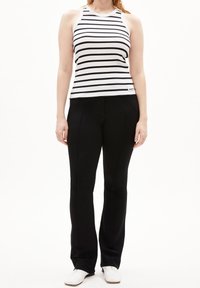 Svart och vit randig linne med ribbad textur, ihop med svarta åtsittande byxor. Modellen bär vita skor.