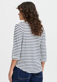 Gestreepte langemouwen top in navyblauw en wit, met een ronde hals, een ronde onderkant en zachte stof met een casual pasvorm. Achteraanzicht getoond.