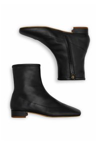 Juodi odiniai auliniai batai iki kulkšnies su šoniniu užtrauktuku, žemu kvadrato kulnu ir smailiu pirštu, parodyti iš šono ir padais ant baltos fono.