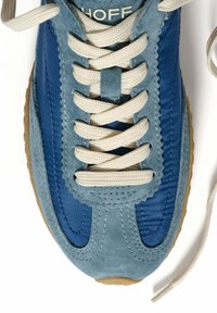 Baskets bleues à la fois en suède et en nylon, avec des lacets crème, des bords festonnés et une semelle en caoutchouc gomme.