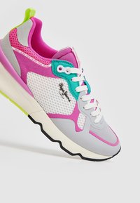 Athletic sneaker med en blandning av grå, rosa och turkosa material, meshpaneler, vita snören och en texturerad sula med neonlysande detaljer.