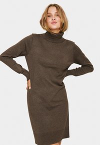 Ruda megzta turtlenecko suknelė su ilgomis rankovėmis, prigludusio silueto, su raukiniais ant rankogalių ir apačios, minkšta tekstūra ir vidutinio ilgio kirpimas.