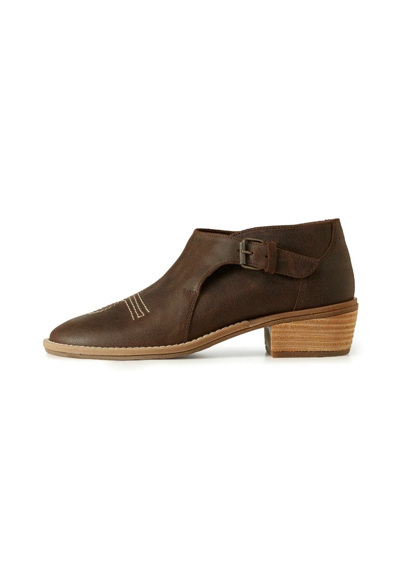 Botín de piel marrón con punta redonda, corte lateral y hebilla ajustable. Presenta un tacón de madera texturizado y costuras decorativas.
