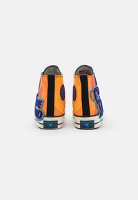 Hohe Sneakers in leuchtendem Orange und Schwarz mit blauen Akzenten, versehen mit auffälliger Stickerei und strukturierten Patches an den Seiten.