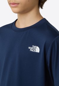 Μπλουζάκι σε σκούρο μπλε χρώμα, κατασκευασμένο από απαλό ύφασμα, με λευκό λογότυπο της The North Face στην πάνω αριστερή πλευρά του στήθους. Κλασικός στρογγυλός γιακάς.