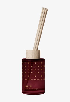 Diffuseur de parfum rouge foncé avec un capuchon en bois et des tiges de roseau naturelles, étiqueté "Skandinavisk JUL" avec des symboles décoratifs dorés.