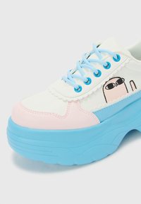 Sapatilha branca com detalhes em rosa e azul. Apresenta bico redondo, sola grossa azul, atacadores azul claro e um gráfico de personagem de cartoon na lateral.