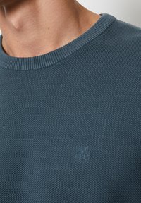 Pullover-Strickpullover in Türkisblau, mit einem strukturierten Muster und einem dezenten Logo-Detail auf der Vorderseite. Hergestellt aus weichem, atmungsaktivem Material.