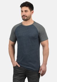 Short-sleeve t-shirt with a blue body and gray raglan sleeves. Made from soft fabric with a smooth texture, featuring a crew neckline.