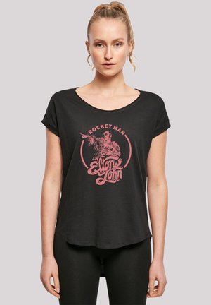 Black t-shirt with short sleeves, round neckline, featuring a pink graphic with "Rocket Man" and "Elton John" text in a cursive style.