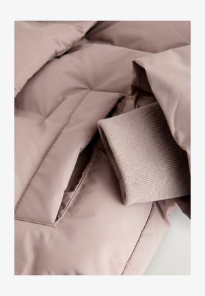 Nafukovacia bunda v jemnej ružovej tkanine, s rebrovaným pleteným manžetou zabudovaným v vrecku. Hladká textúra s prešívaním.