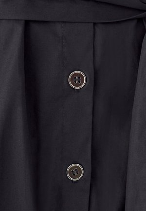 Czarna tkanina o gładkiej fakturze, z dwoma srebrnymi metalowymi guzikami z czterema dziurkami każdy oraz złożonym pasem.