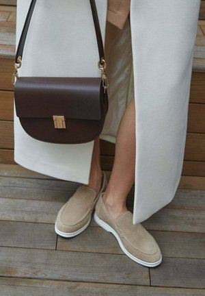 Beige suede slip-on shoes with white soles, paired with a brown leather handbag featuring a gold clasp and a crossbody strap.